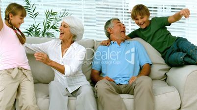 Children jumping on grandparents on the couch