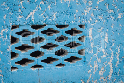 Blue aged street wall with black brick holes