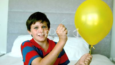 Boy piercing his yellow balloon and getting a fright