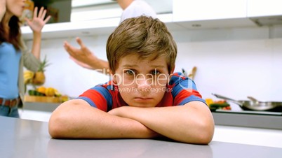 Sad boy with arms folded while parents quarreling