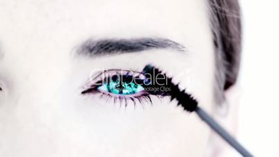 Blue eyed woman making up with mascara