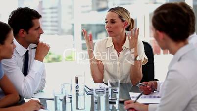 Businesswoman gesturing in front of colleagues