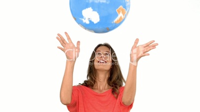 Woman throwing a globe in the air on white background