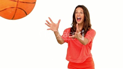 Cheerful woman catching a basketball on white background