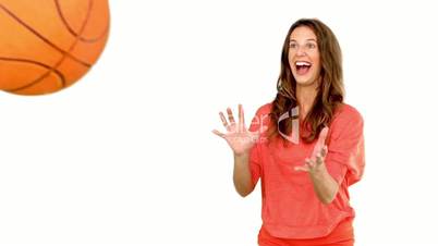 Smiling woman catching a basket ball on white background