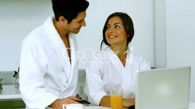 Cute couple having their breakfast while using a laptop