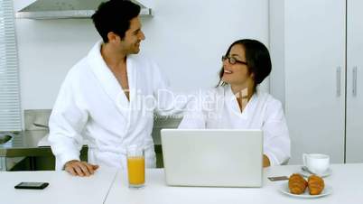 Man kissing his girlfriend while she is having a breakfast