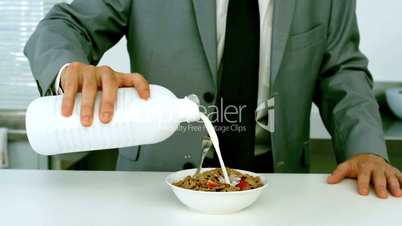 Businessman pouring milk into his cereals