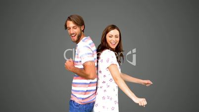 Friends dancing back to back on grey background