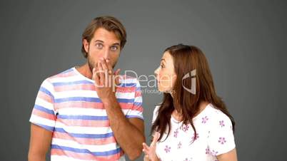 Woman telling her friend a massive secret on grey background