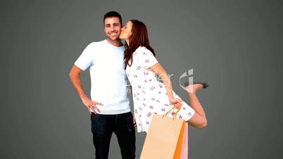 Man being kissed on his cheek by his girlfriend on grey background