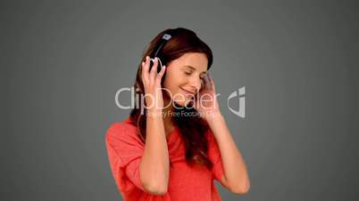 Woman listening to music on grey background