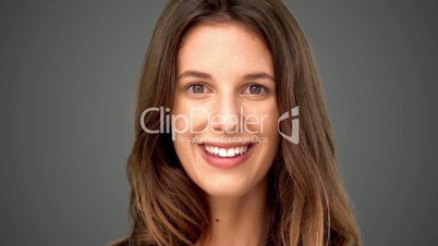 Surprised woman smiling on grey background