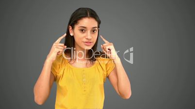 Woman pointing  to her temples on grey background