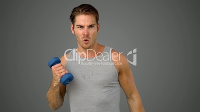 Man exercising with dumbbell on grey background