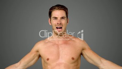 Sportsman raising his arms on grey background