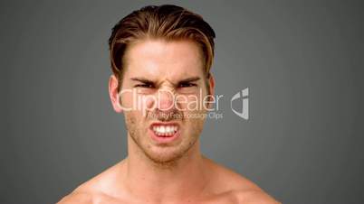 Young man showing his anger on grey background