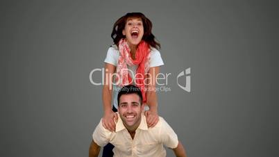 Woman jumping on the back of her friend on grey background
