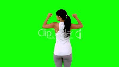 Woman in sportswear tensing her arms on green screen