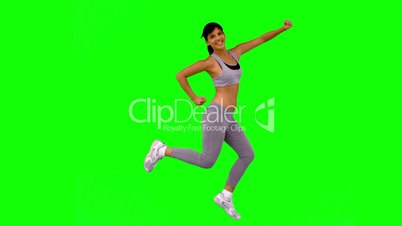 Athletic woman jumping and posing on green screen