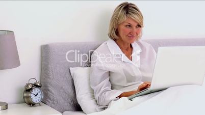 Mature woman using laptop in her bedroom