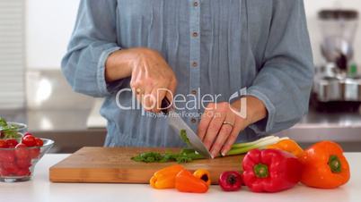 Woman slicing spring onion with knife