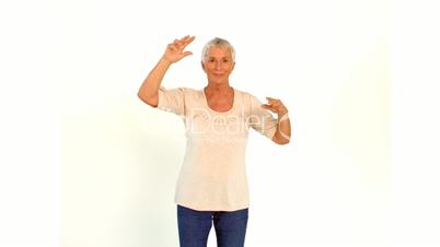 Senior woman dancing against white background