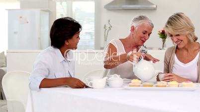 Mature woman pouring tea to her friends cup