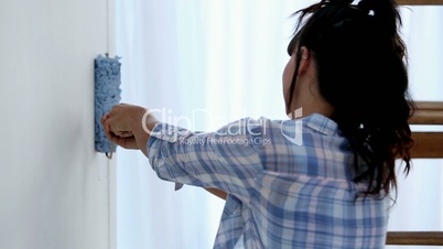 Young woman painting her wall