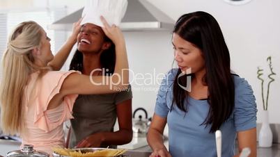 Woman putting a chef hat on her friend head