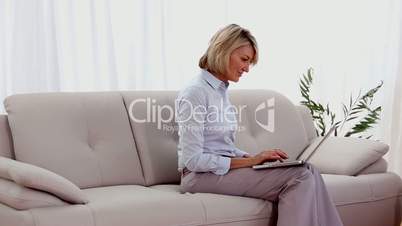 Mature woman on the couch using a laptop