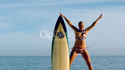 Female surfer leaping out from behind her board