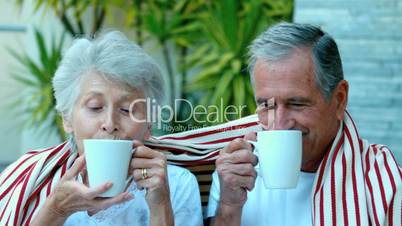 Retired couple enjoying coffee outside
