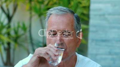 Retired man drinking water outside