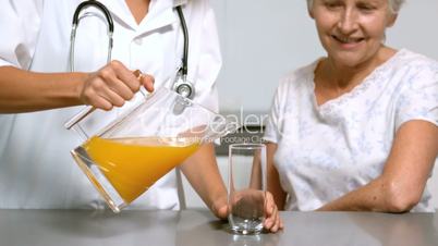 Home help pouring juice for patient in kitchen
