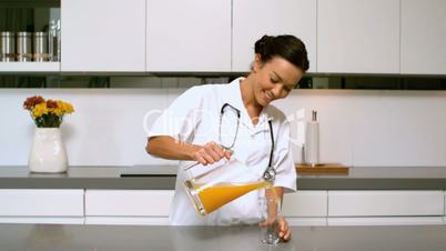 Home nurse pouring glass of orange juice in kitchen