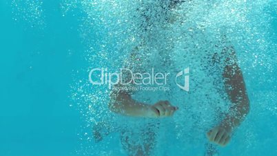 Brunette woman floating underwater in blue bathing suit