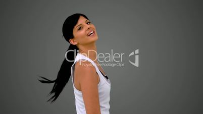 Fit brunette smiling at the camera and shaking her hair