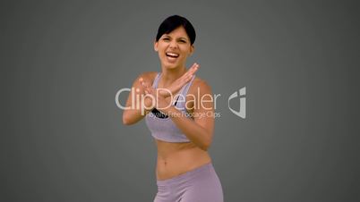 Fit brunette making martial arts pose and smiling