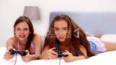 Excited girls playing video games on bed
