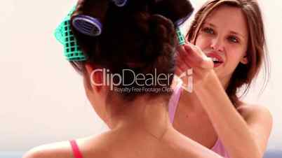 Girl fixing her friends hair rollers