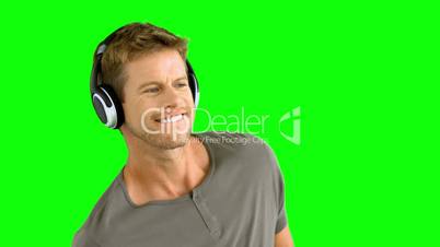 Attractive man with headphones listening to music on green screen