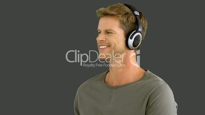Attractive man with headphones listening to music on grey screen