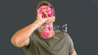 Man blowing pink confetti on grey screen