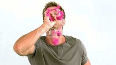 Man blowing pink confetti on white background