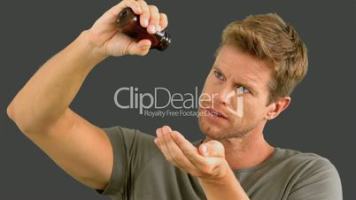 Man pouring out pills on grey screen