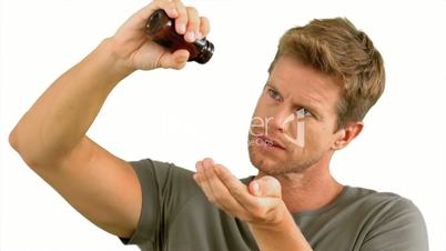 Man pouring out pills on white background