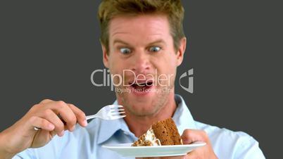 Attractive man about to eat a cake on grey screen