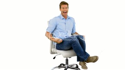 Smiling man turning on swivel chair on white background