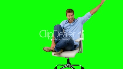 Smiling man cheering and turning on swivel chair on green screen